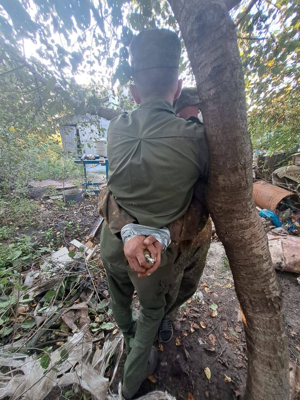 Предположительно, украинские военнопленные, связанные друг с другом. У одного в руке граната без предохранительной чеки